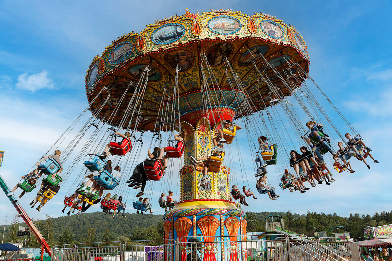 A photo of the fair's swing ride. Dozens of fairgoers go around in circles with a blue sky in the foreground.